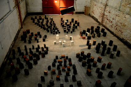 Large warehouse space with hundreds of speakers arranged like an audience around a central arrangement of white speakers